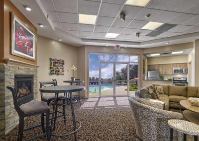 Community room in Village Square Apartments clubhouse with kitchenette and view of the pool