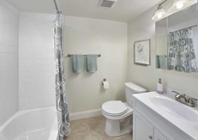 Large bathroom with white sink and vanity, towel bar, and overhead lighting