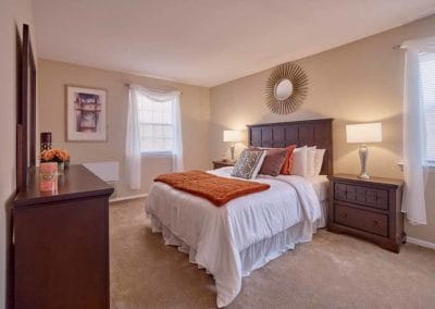 Furnished master bedroom with large windows and plush carpeting