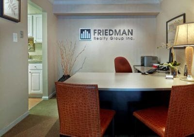 Leasing office with large desk and red chairs in front of Friedman Realty Group sign