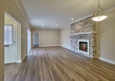 Living space at Willowyck Apartments with shining hardwood floors and brick fireplace