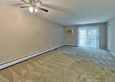 Huge living area with ceiling fan and baseboard heating and lots of natural light coming sliding glass doors that lead to private balcony