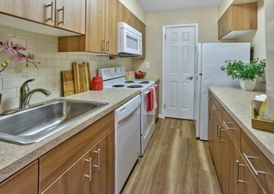 Beautifully renovated galley kitchen with vinyl flooring and contemporary tile backsplash