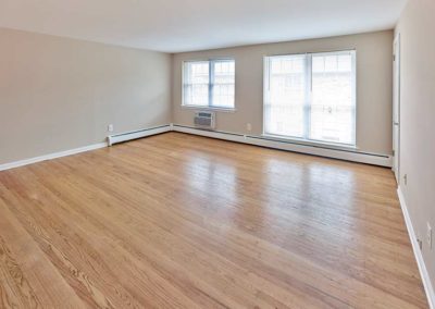 Spacious living room with hardwood flooring and plenty of natural light from large windows