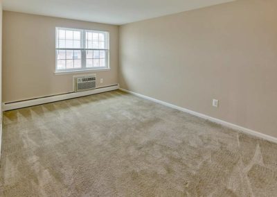 Plush carpeted bedroom with air conditioning unit and large window