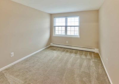 Large window fills carpeted bedroom with natural light at Prospect Park apartment for rent