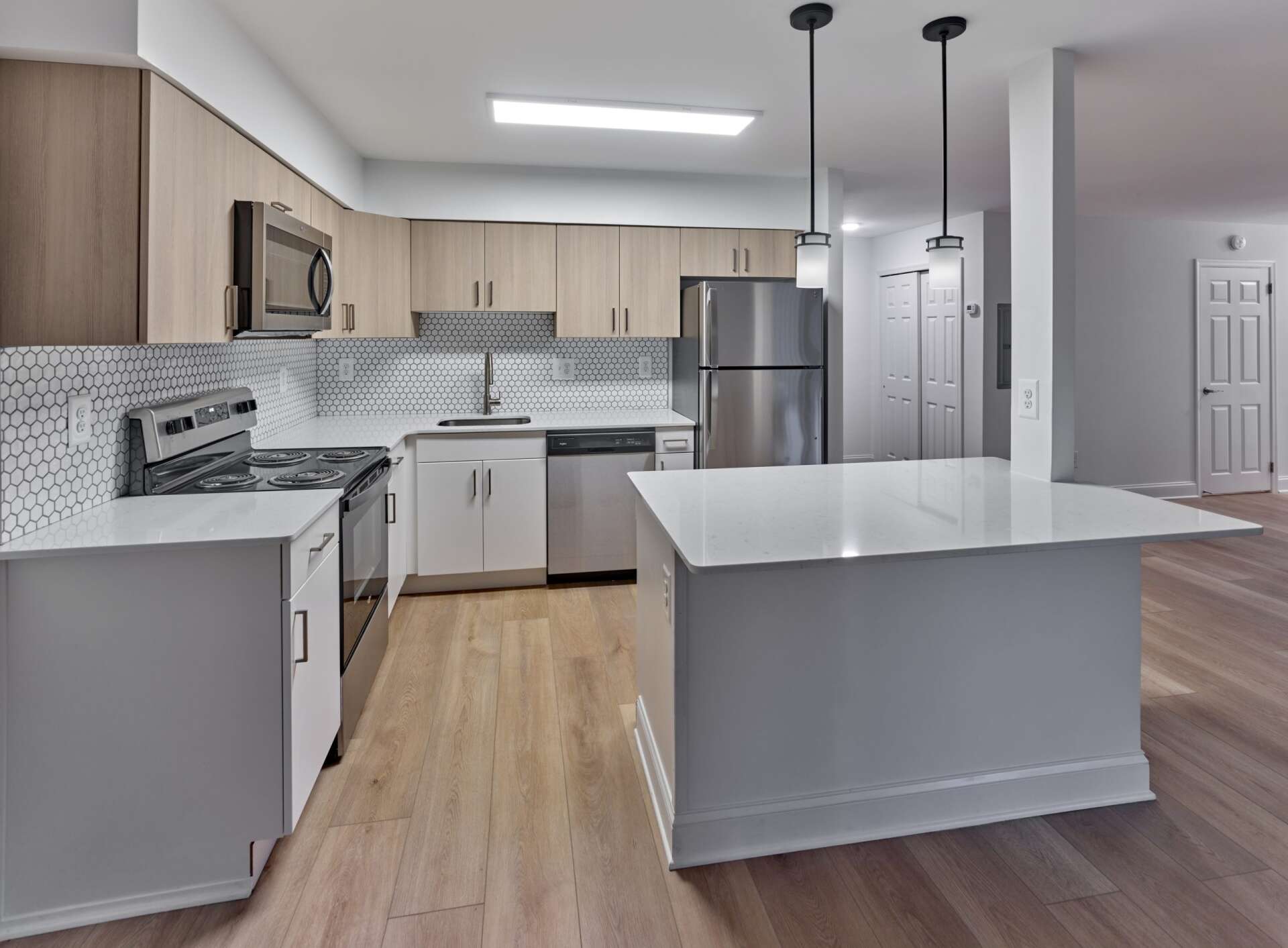 Renovated apartment kitchen with white cabinets, hardwood floors, and an island