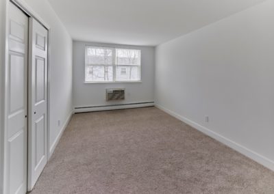 Carpeted bedroom with large window at Brookdale Apartments