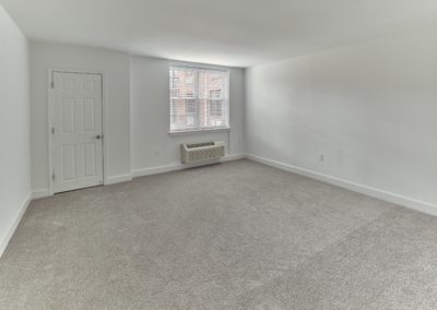 Spacious bedroom with carpet flooring and a large window with window treatments